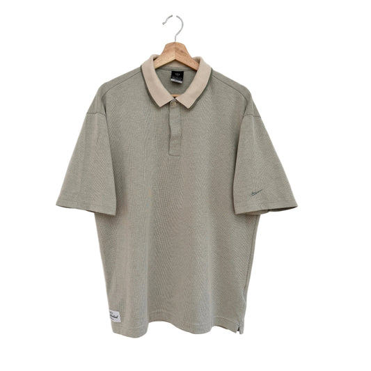 Green polo shirt with beige collar on a hanger against a white background