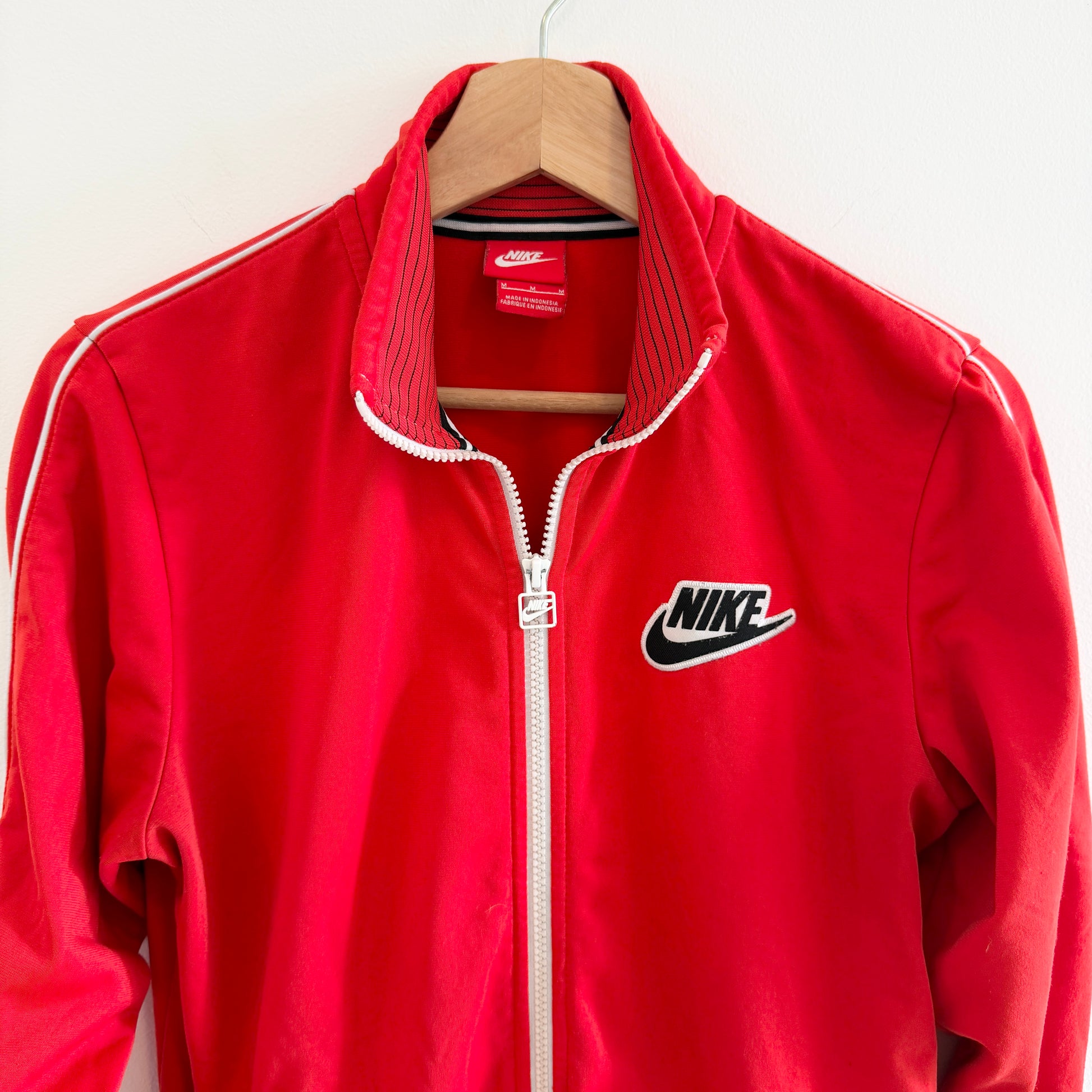 Red Nike jacket on a hanger against a white background