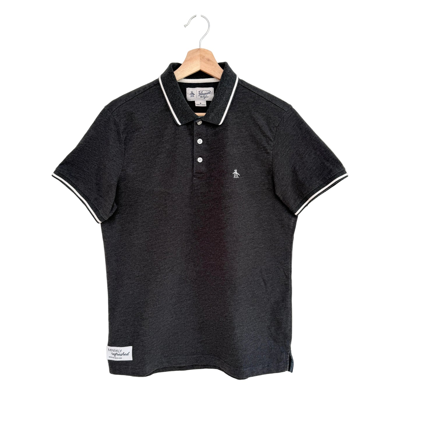 Grey polo shirt with white trim on a hanger against a white background