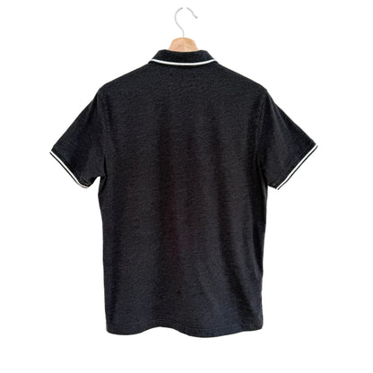 Grey polo shirt with white trim on a hanger against a white background