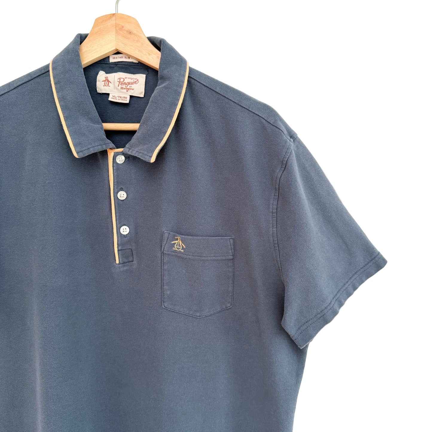 Blue polo shirt with a collar on a hanger against a white background