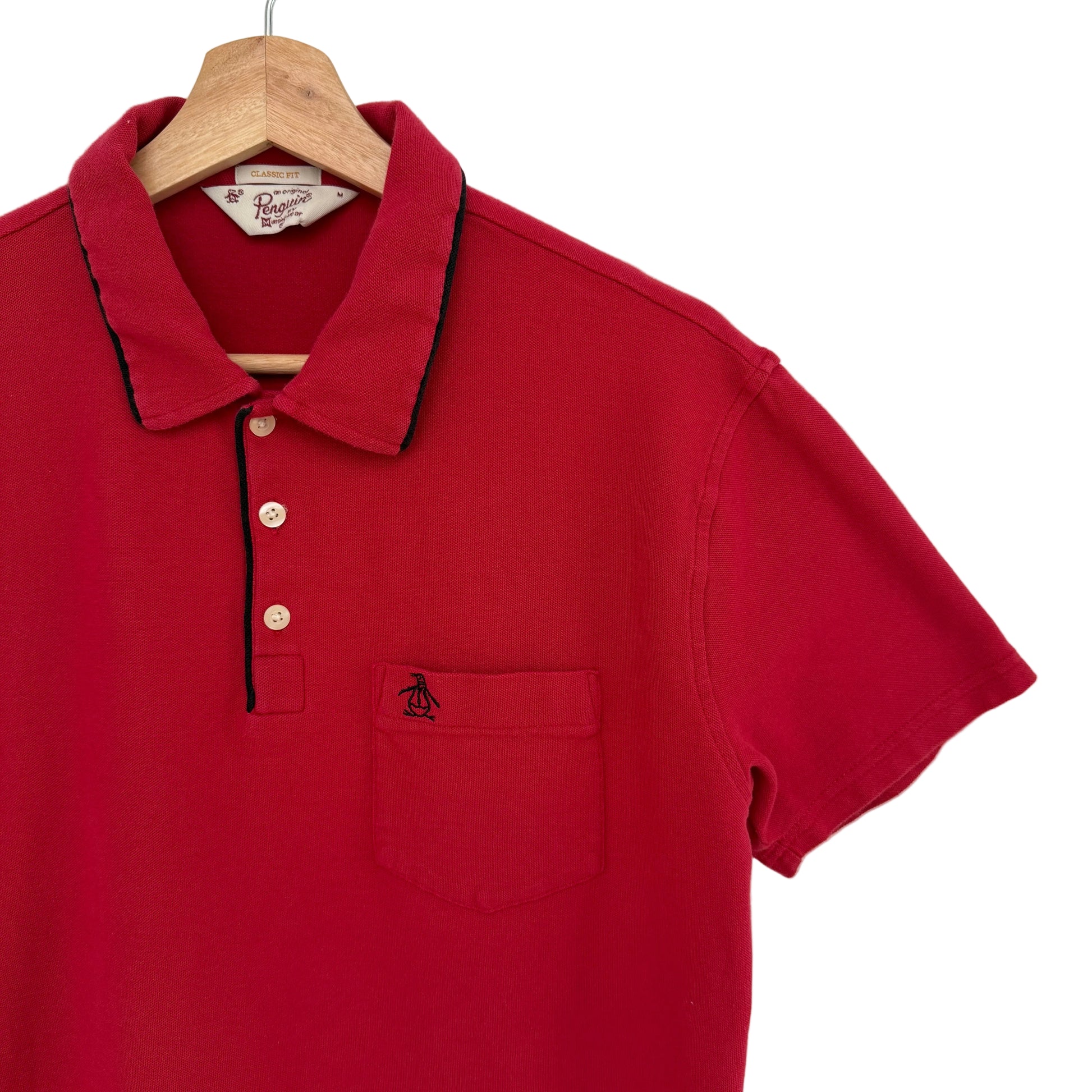 Red polo shirt on a hanger against a white background