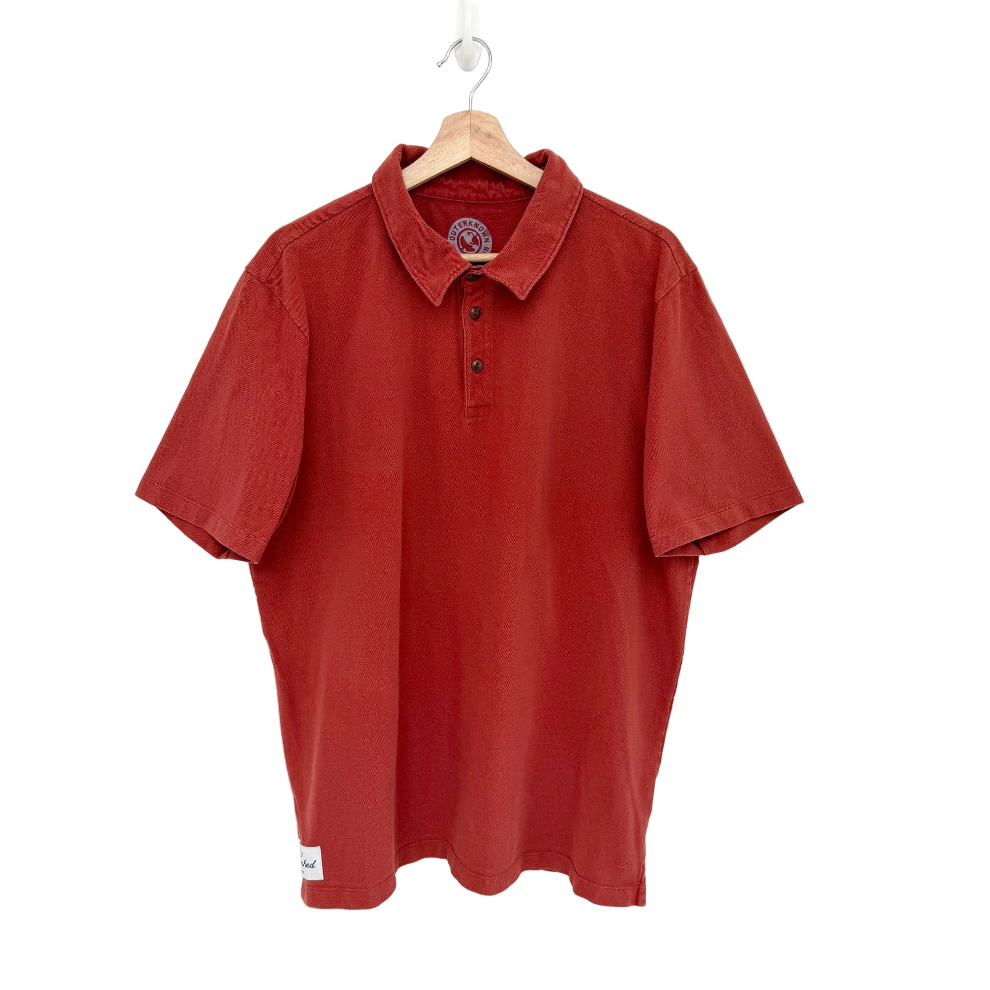 Red polo shirt on a hanger against a white background