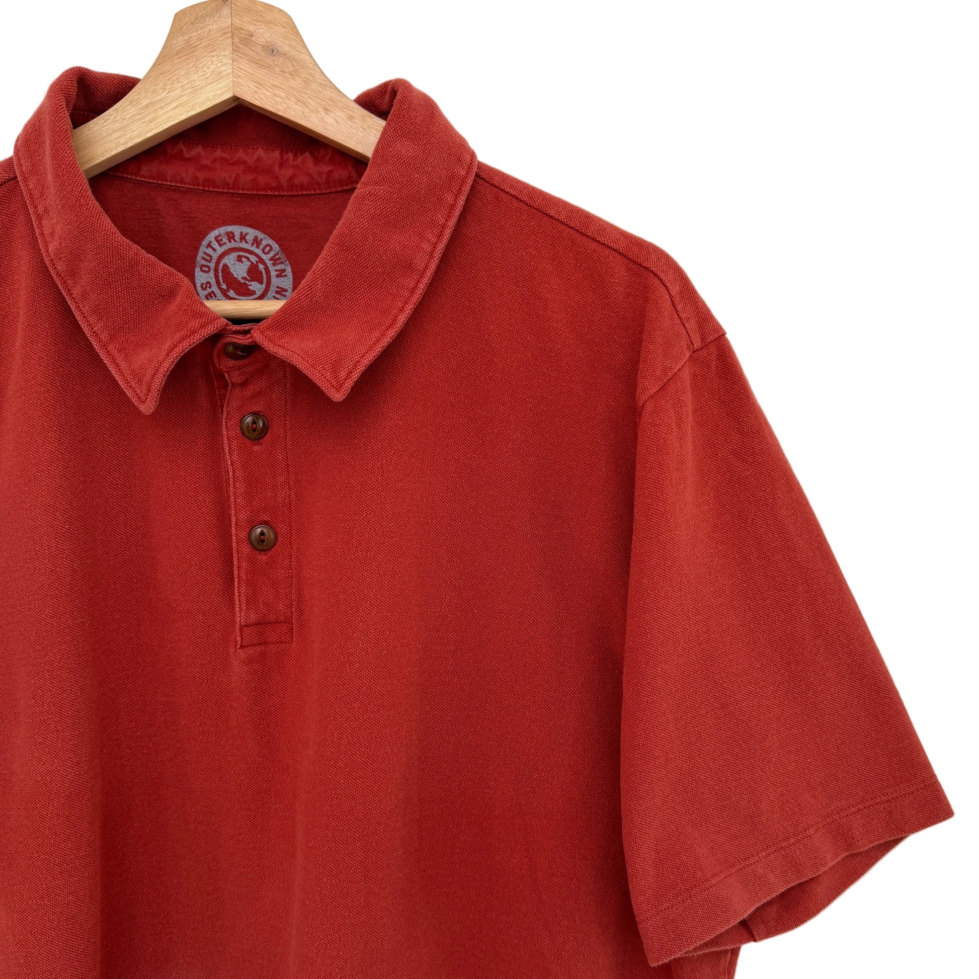 Red polo shirt on a wooden hanger against a white background