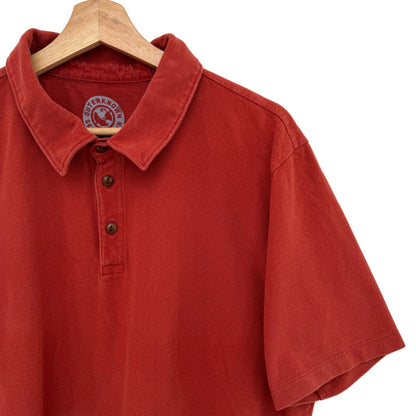 Red polo shirt on a wooden hanger against a white background