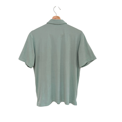 Green polo shirt on a hanger against a white background