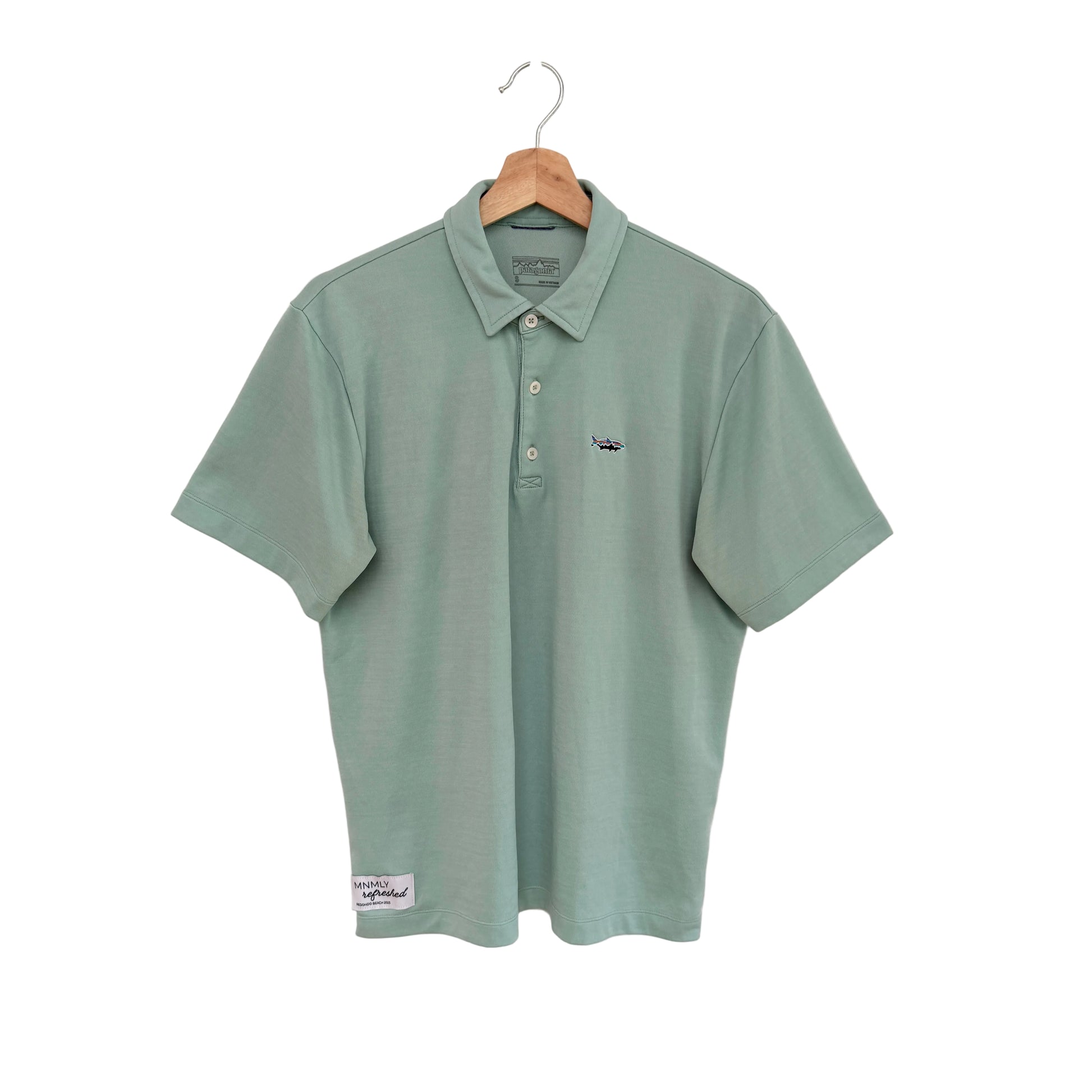 Green polo shirt on a hanger against a white background