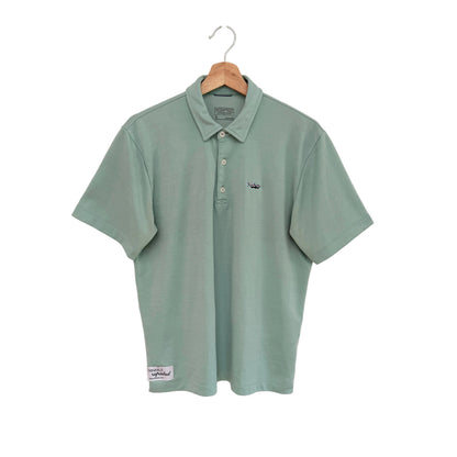 Green polo shirt on a hanger against a white background