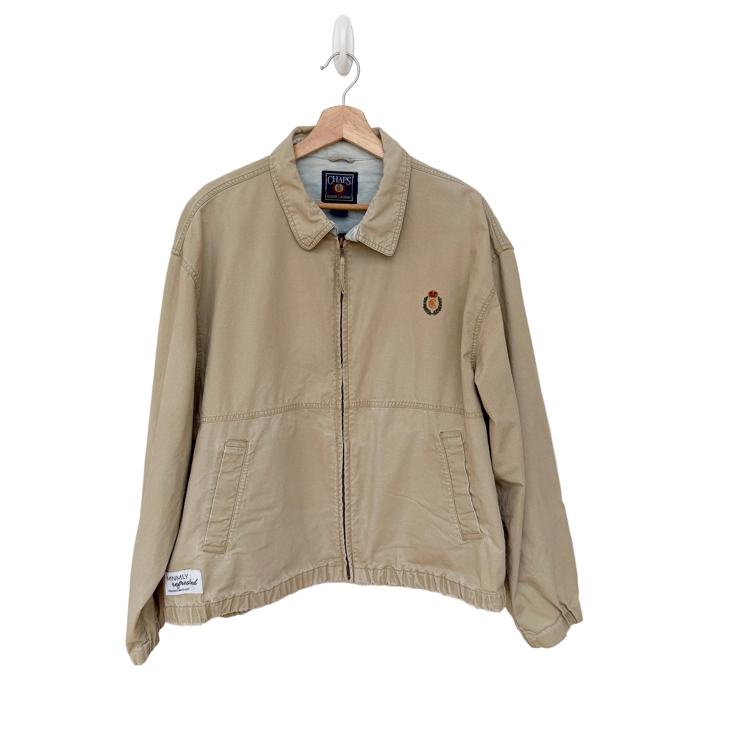 Beige jacket with a brand logo on a hanger against a white background