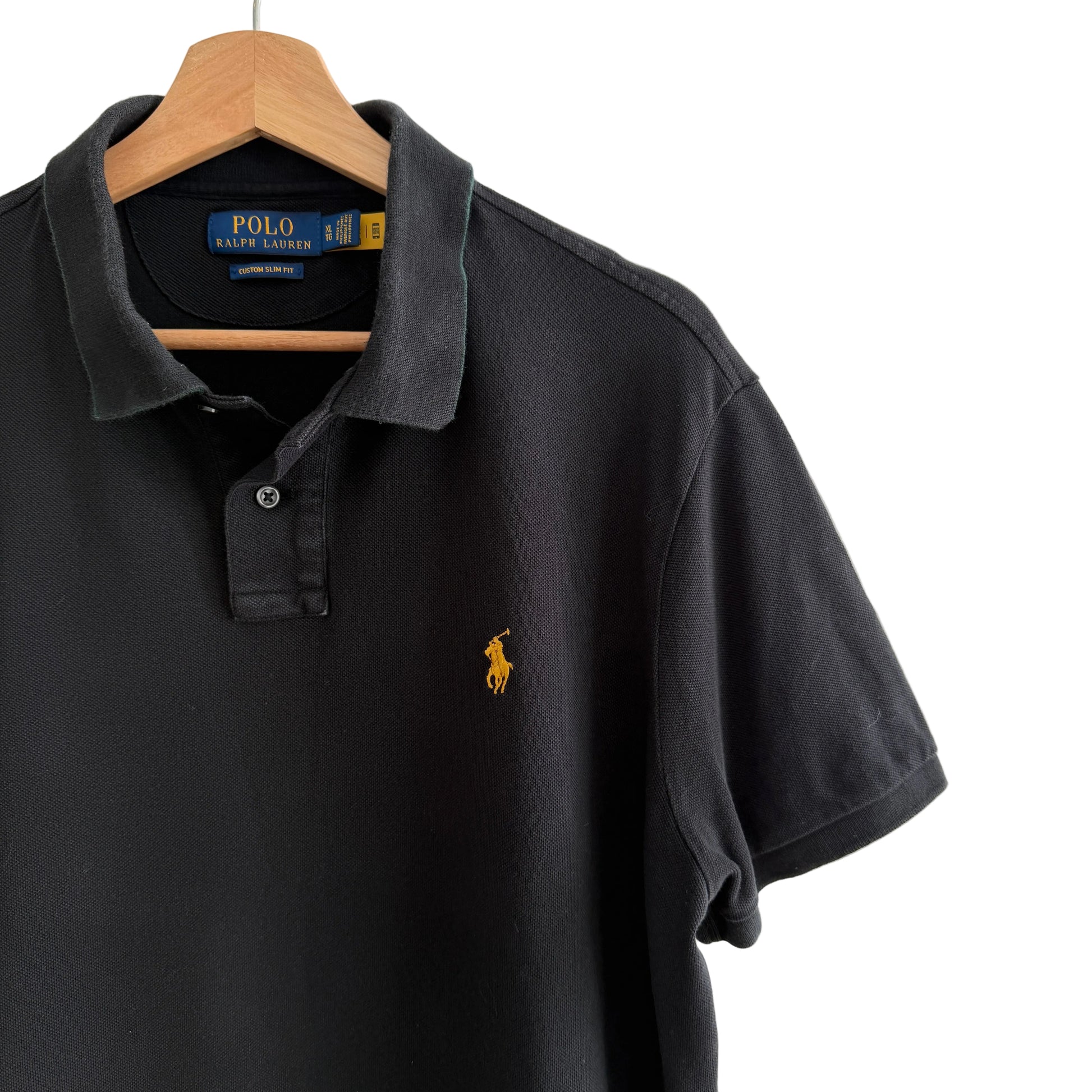Black Polo shirt with yellow logo on a hanger against a white background
