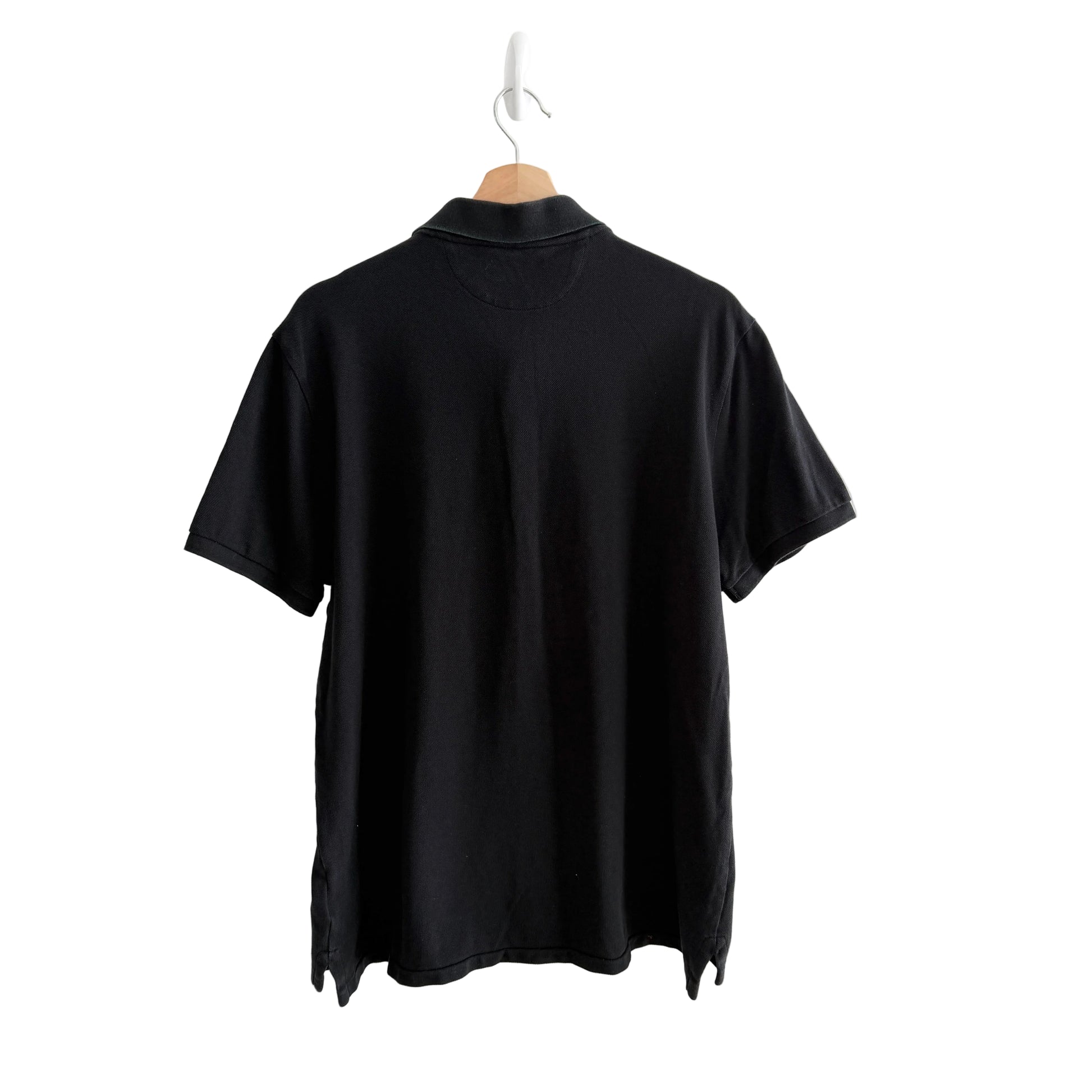Black golf shirt on a hanger against a white background