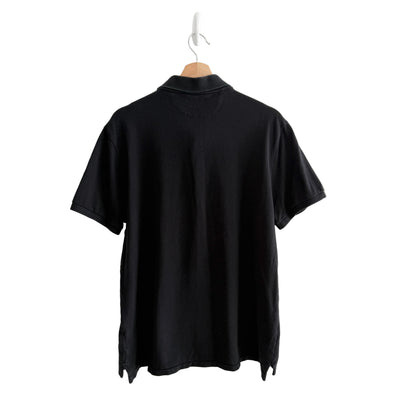 Black golf shirt on a hanger against a white background