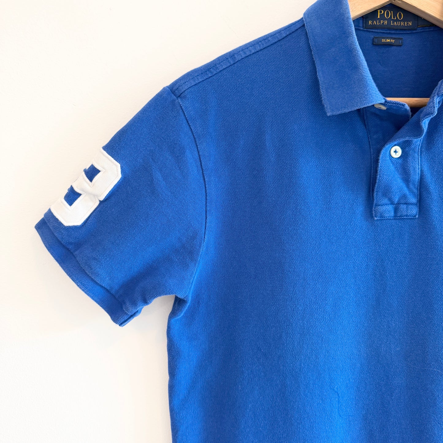 Blue polo shirt with a brand label on a white background
