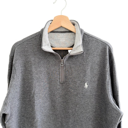 Gray pullover with a small logo on a hanger against a white background