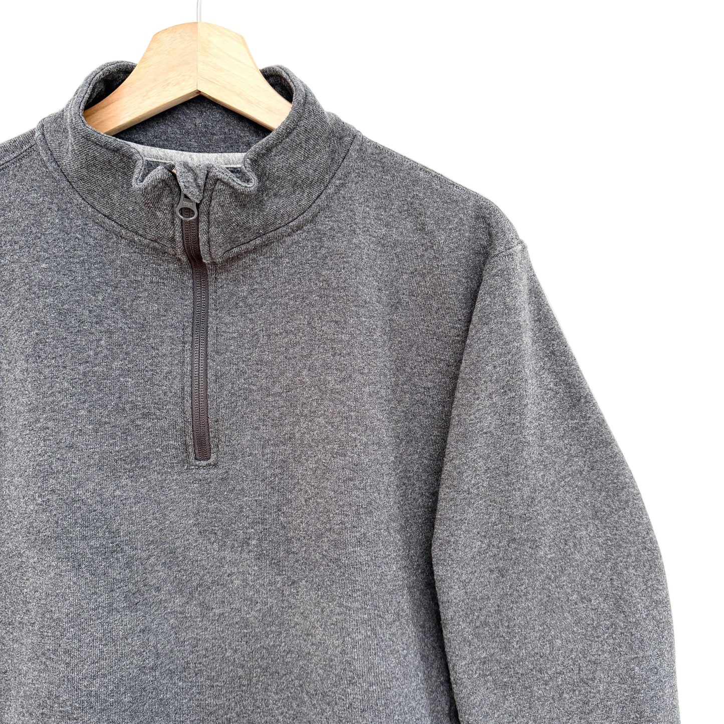 Gray pullover sweatshirt on a wooden hanger against a white background