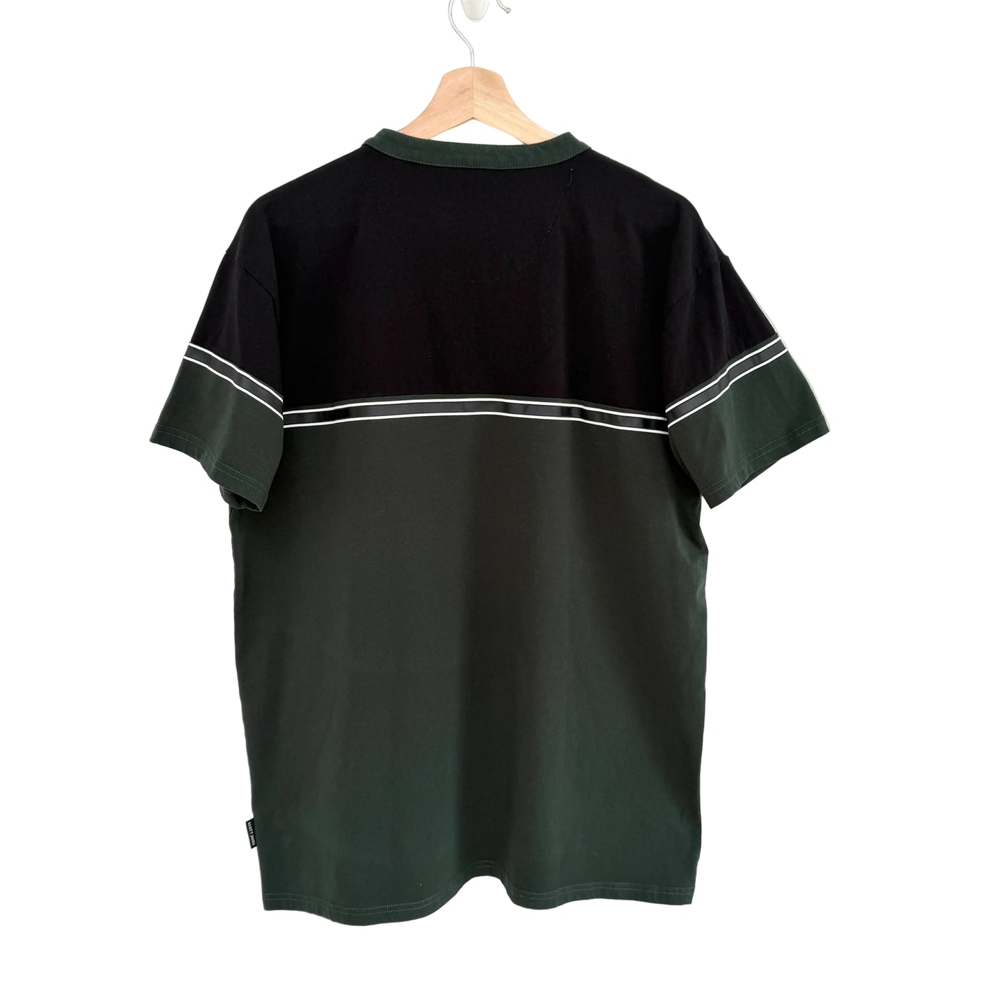 Black t-shirt with white trim on a hanger against a white background
