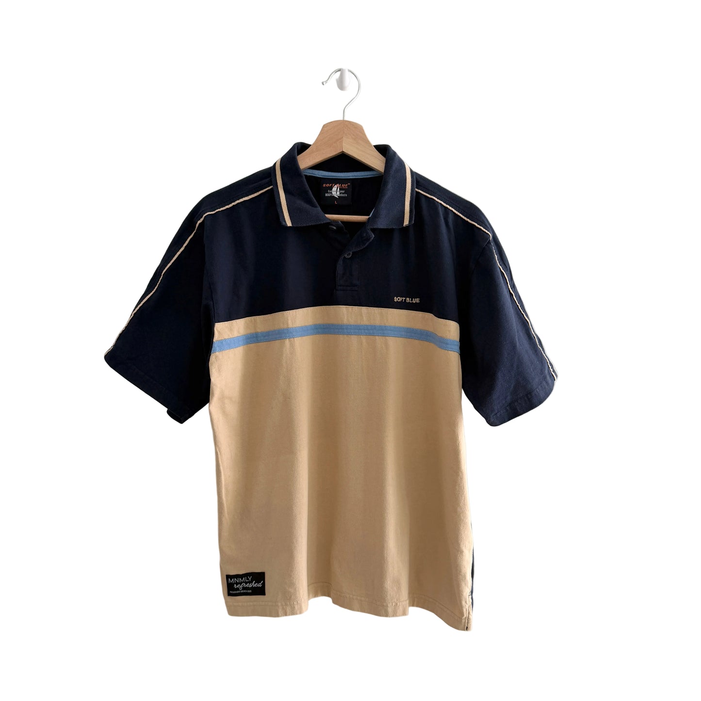 Two-tone polo shirt with navy and beige colors on a hanger against a white background