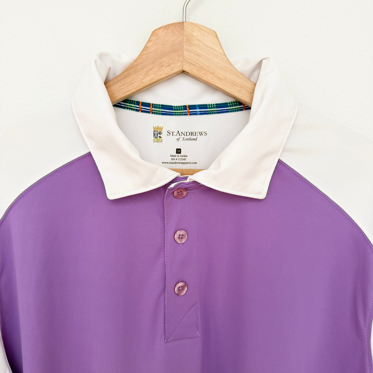 Purple polo shirt with white collar on a hanger against a white background