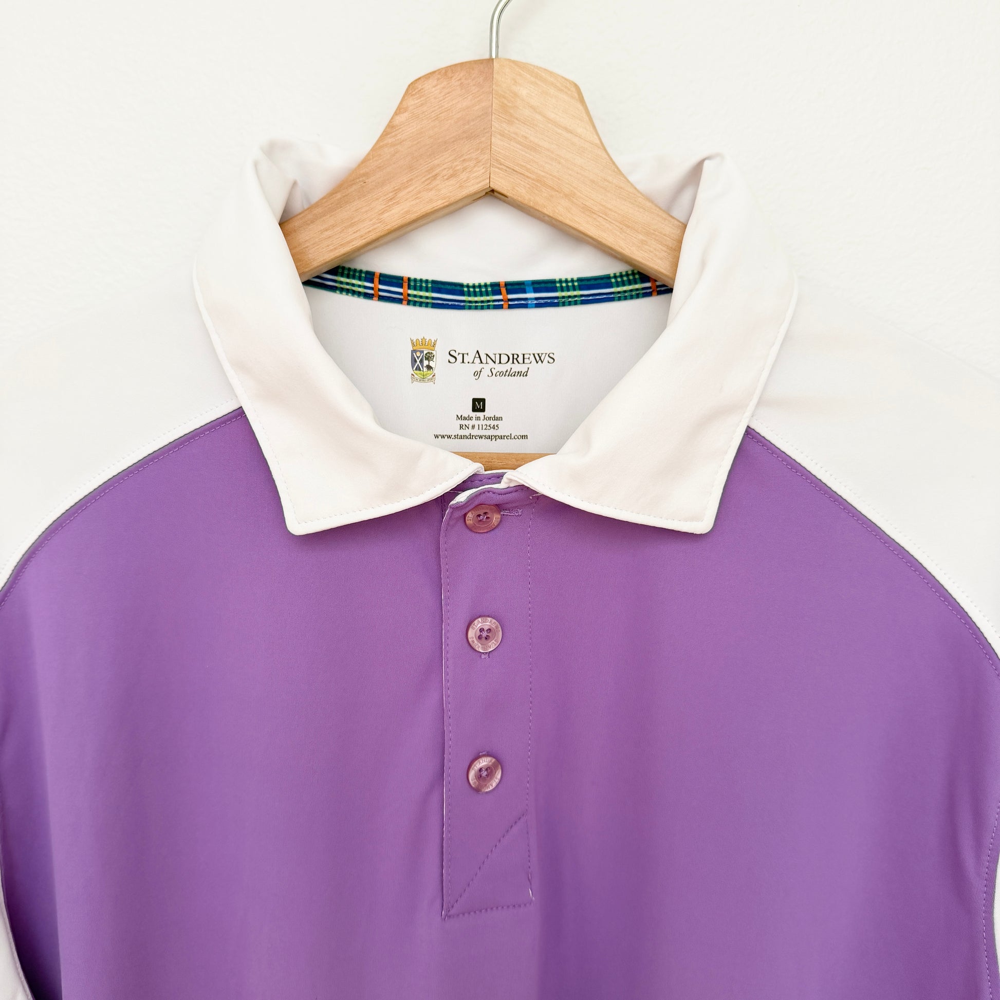 Purple polo shirt with white collar on a hanger against a white background