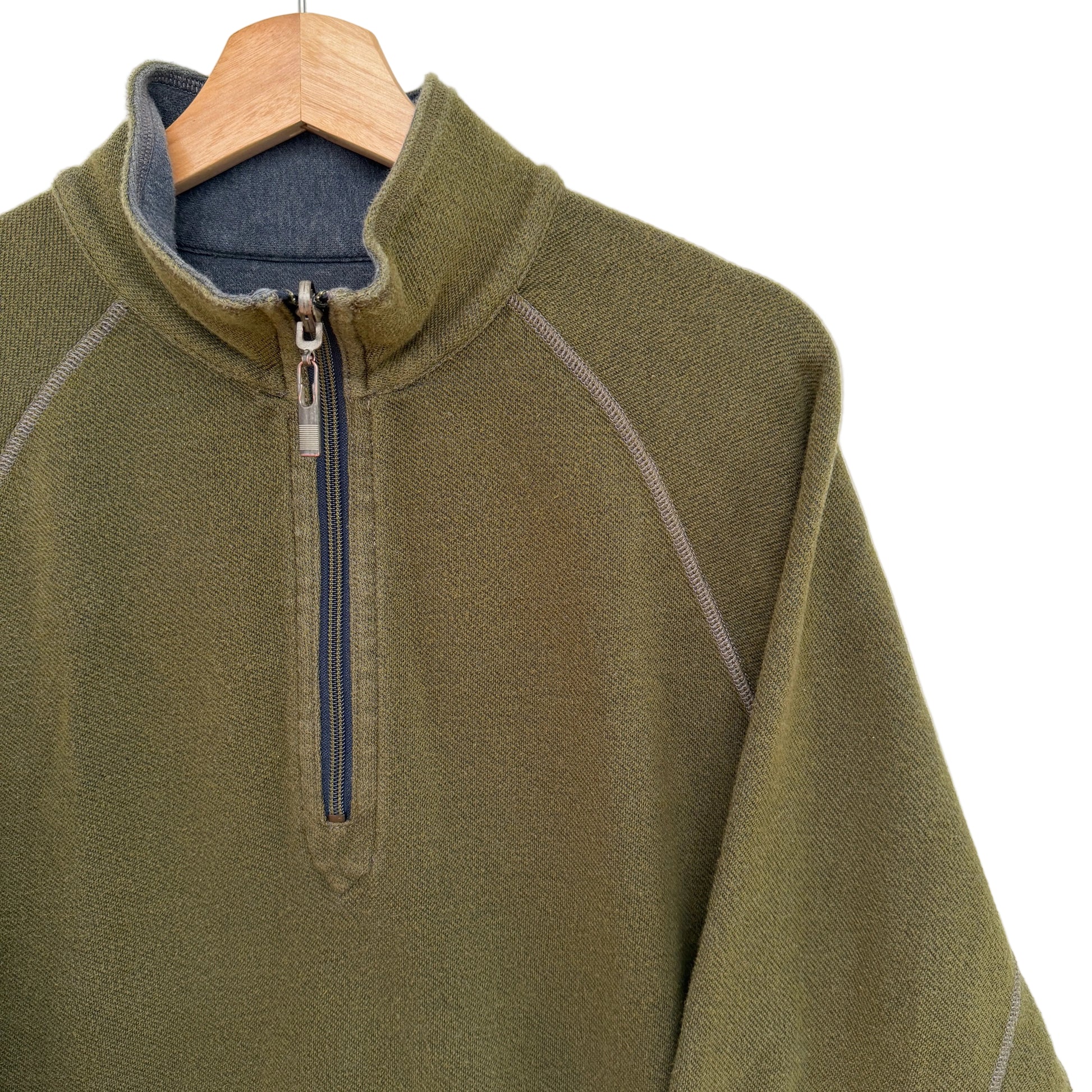 Green pullover with a quarter zip on a wooden hanger against a white background