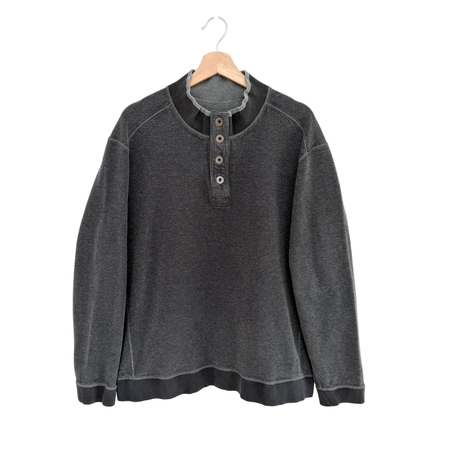 Gray pullover with button details on a hanger against a white background