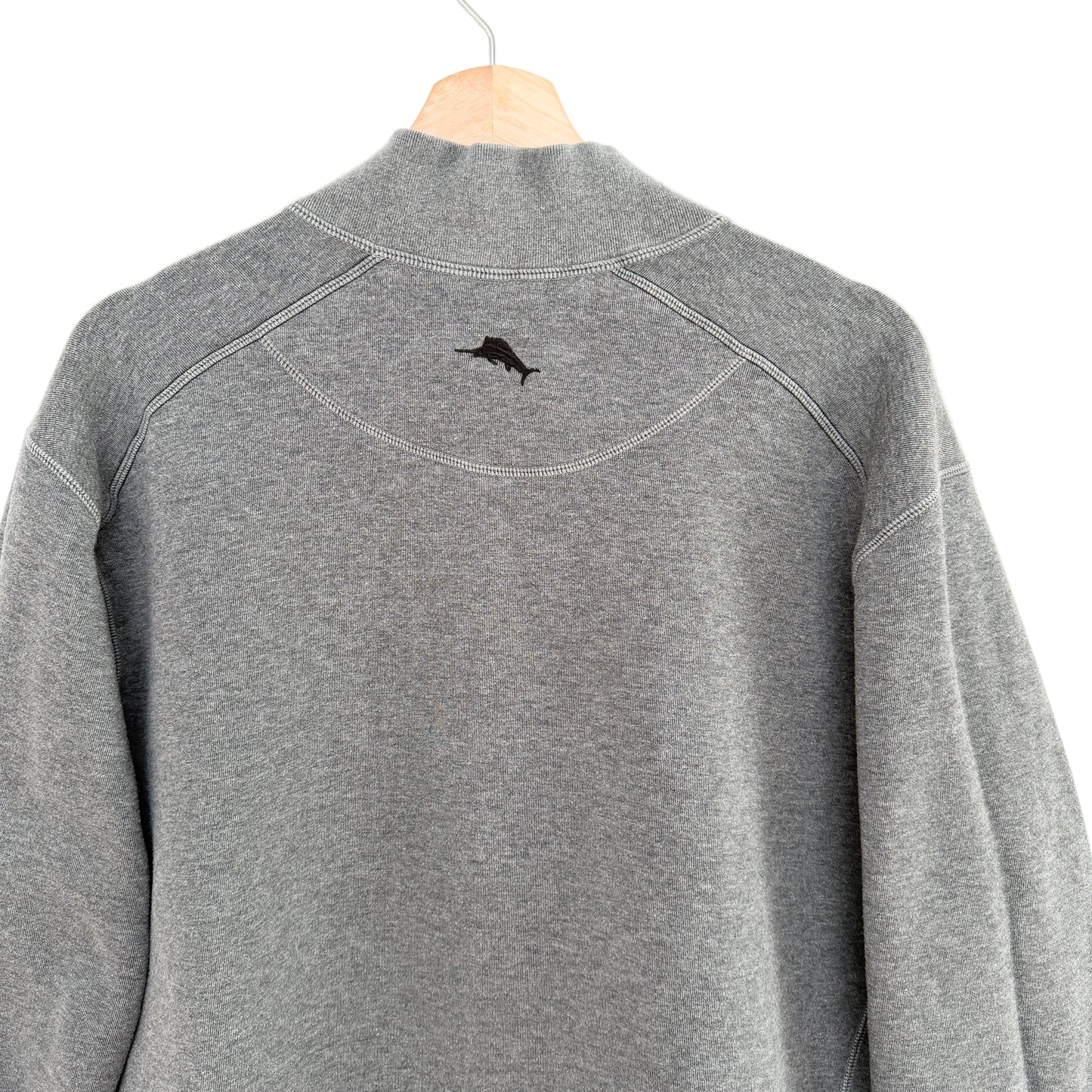 Gray pullover with a small logo on the chest area, hanging against a white background.