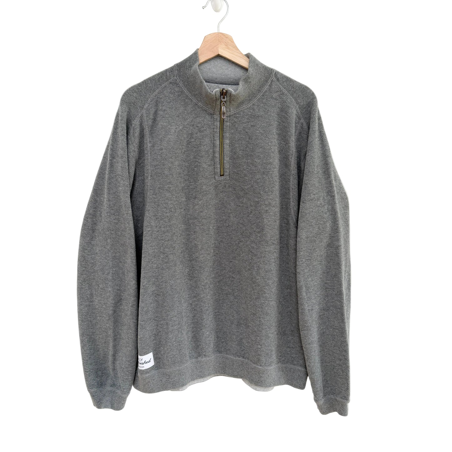 Gray pullover with a quarter zip on a hanger against a white background