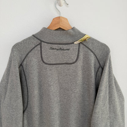 Gray fleece pullover with 'Tommy Bahama' branding on a wooden hanger against a white background