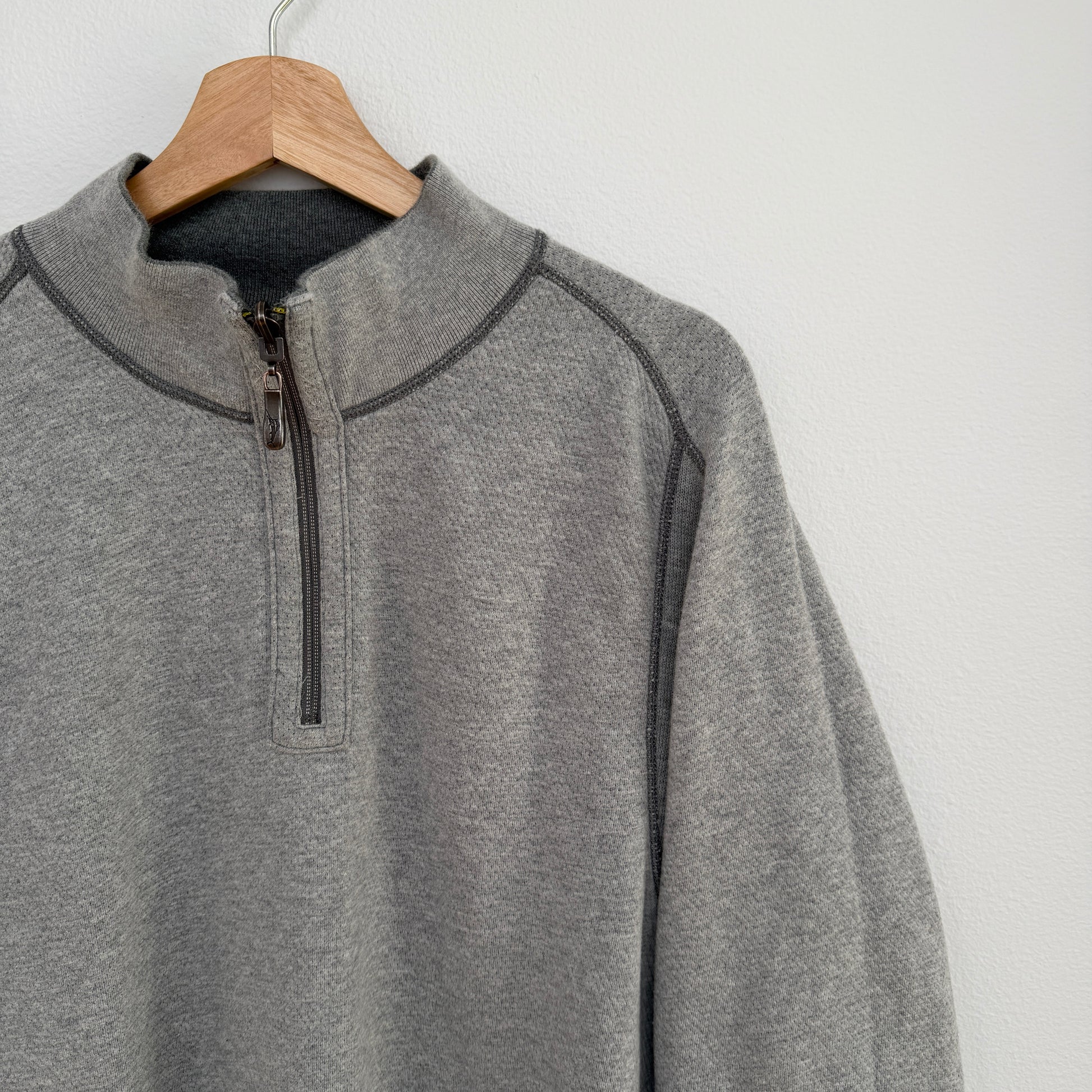 Gray pullover with a quarter zip on a wooden hanger against a white background