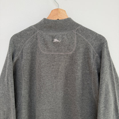 Gray fleece pullover with a brand logo on a wooden hanger against a light gray background