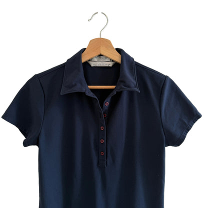 Navy blue polo shirt on a wooden hanger against a white wall
