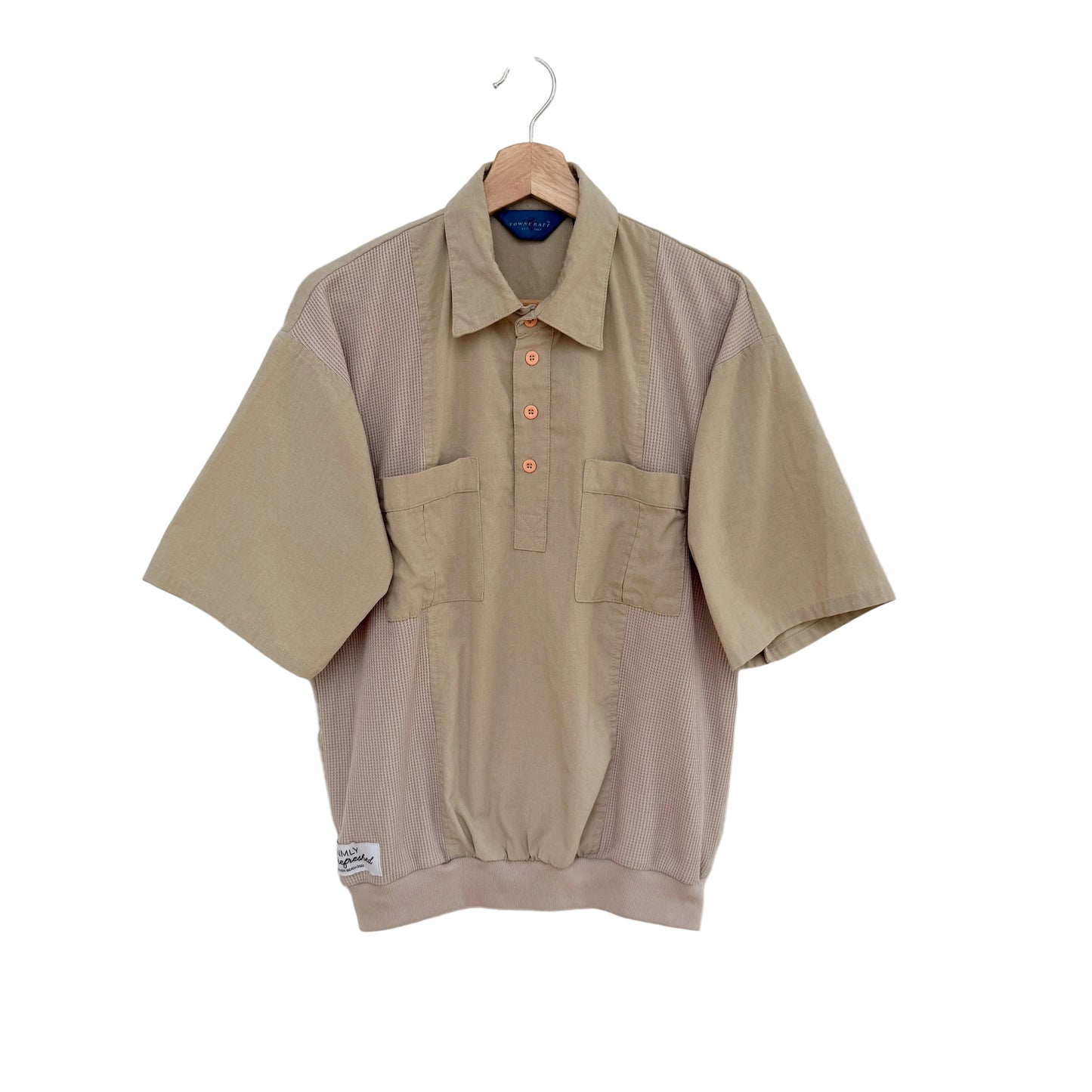 Beige short-sleeve shirt on a hanger against a white background