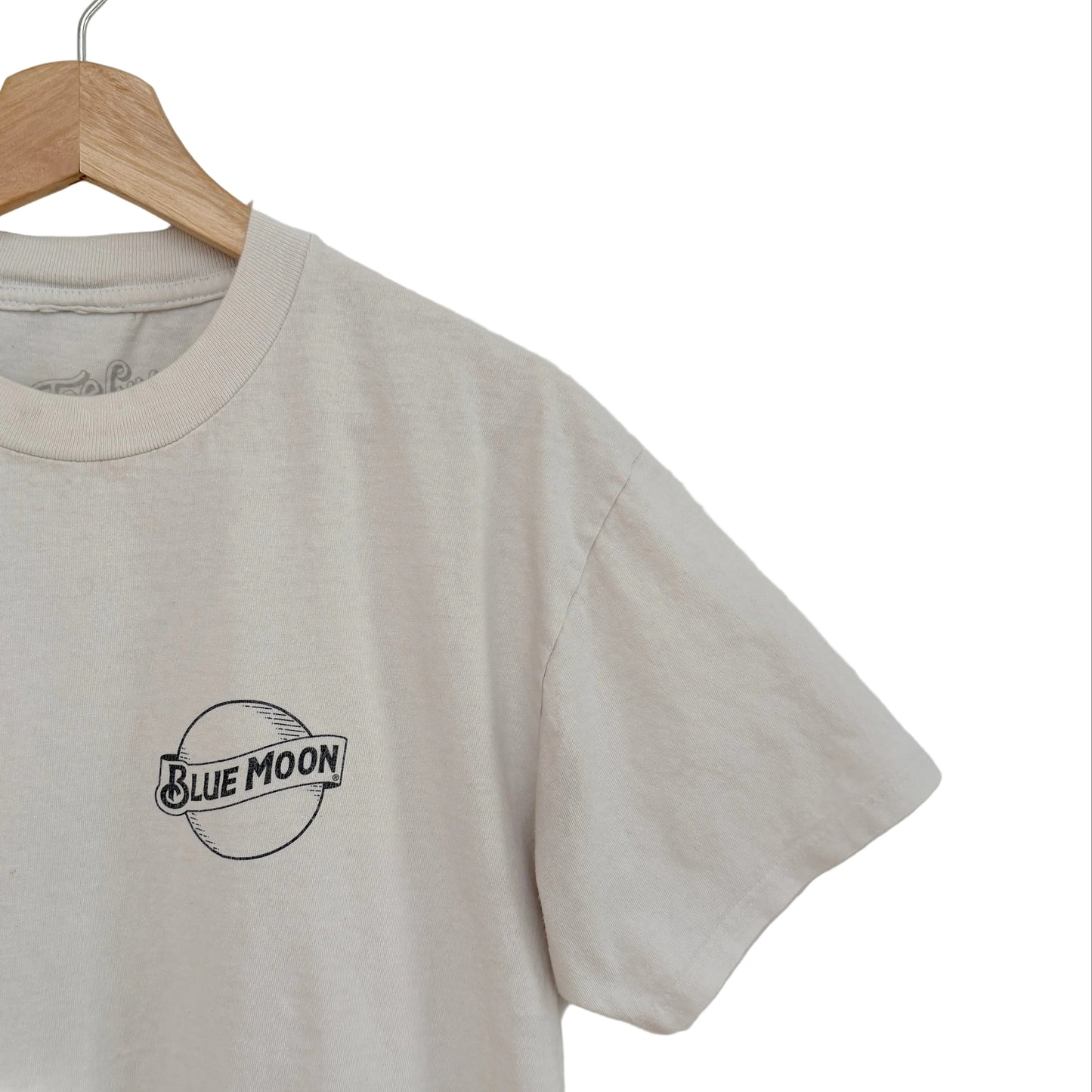 White t-shirt with 'Blue Moon' logo on a wooden hanger against a white background