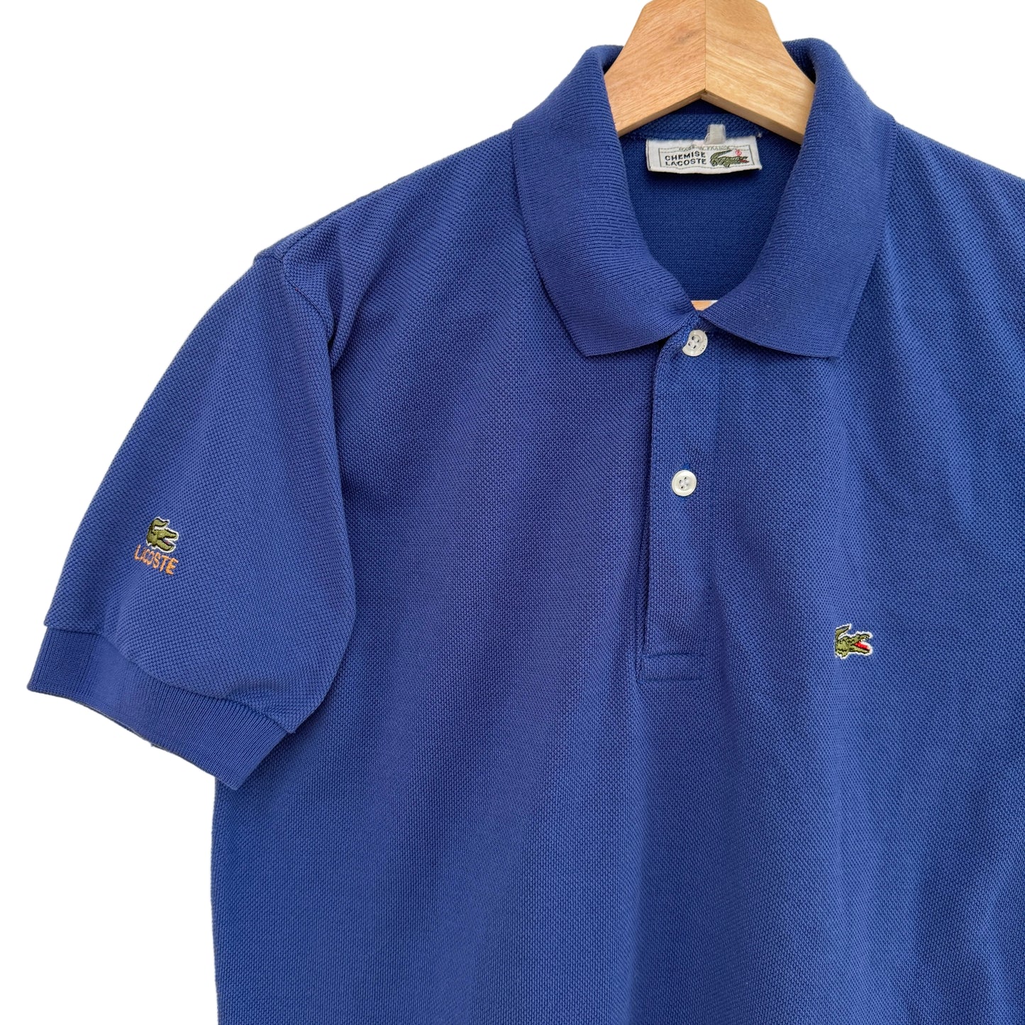 Blue polo shirt on a hanger against a white background