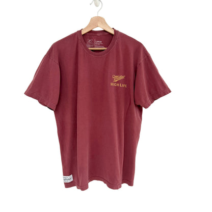 Red t-shirt with 'Miller High Life' logo on a hanger against a white background