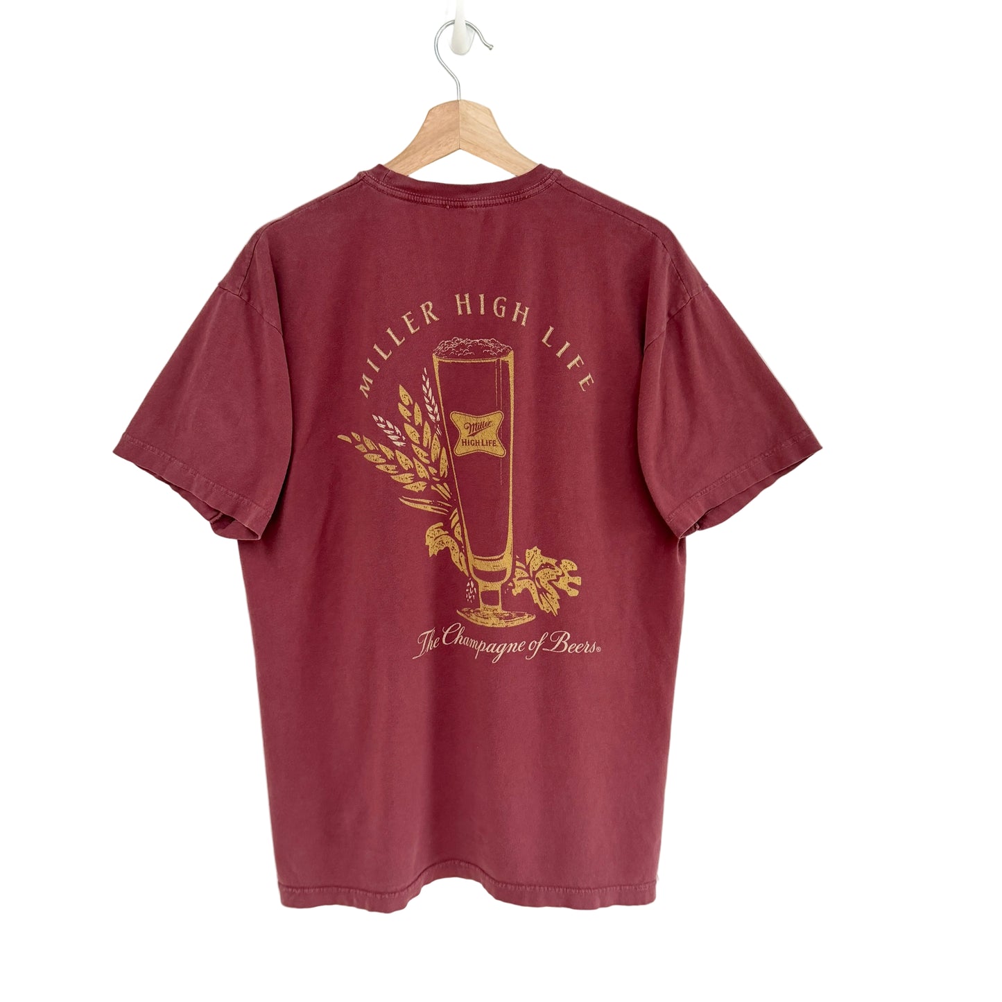 Maroon t-shirt with gold graphic and text on a white background