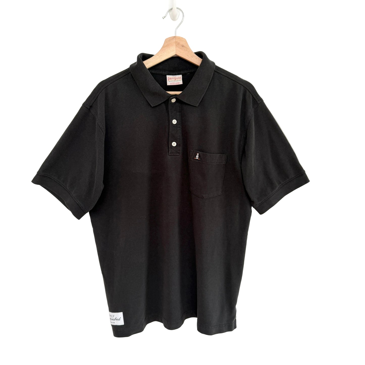 Black polo shirt on a hanger against a white background