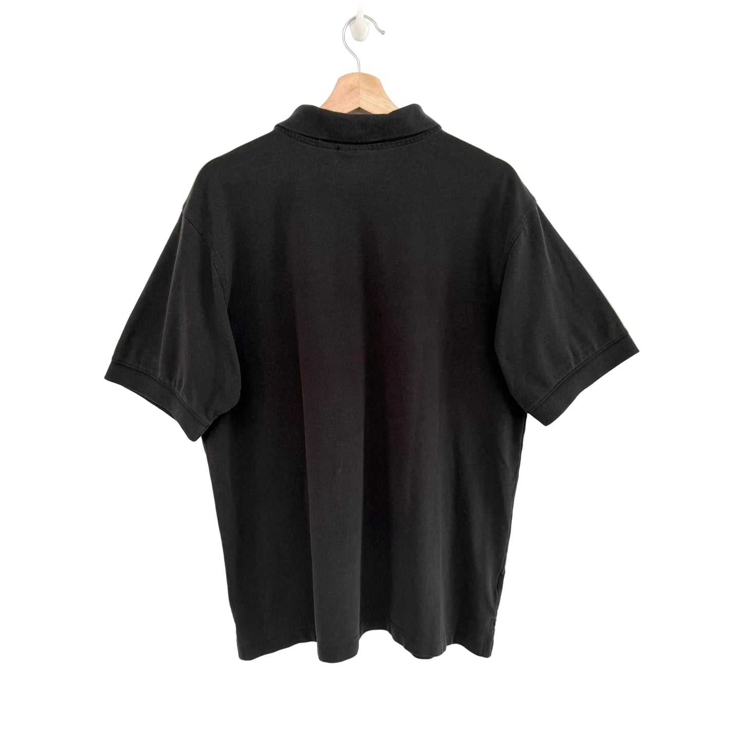 Black polo shirt on a hanger against a white background