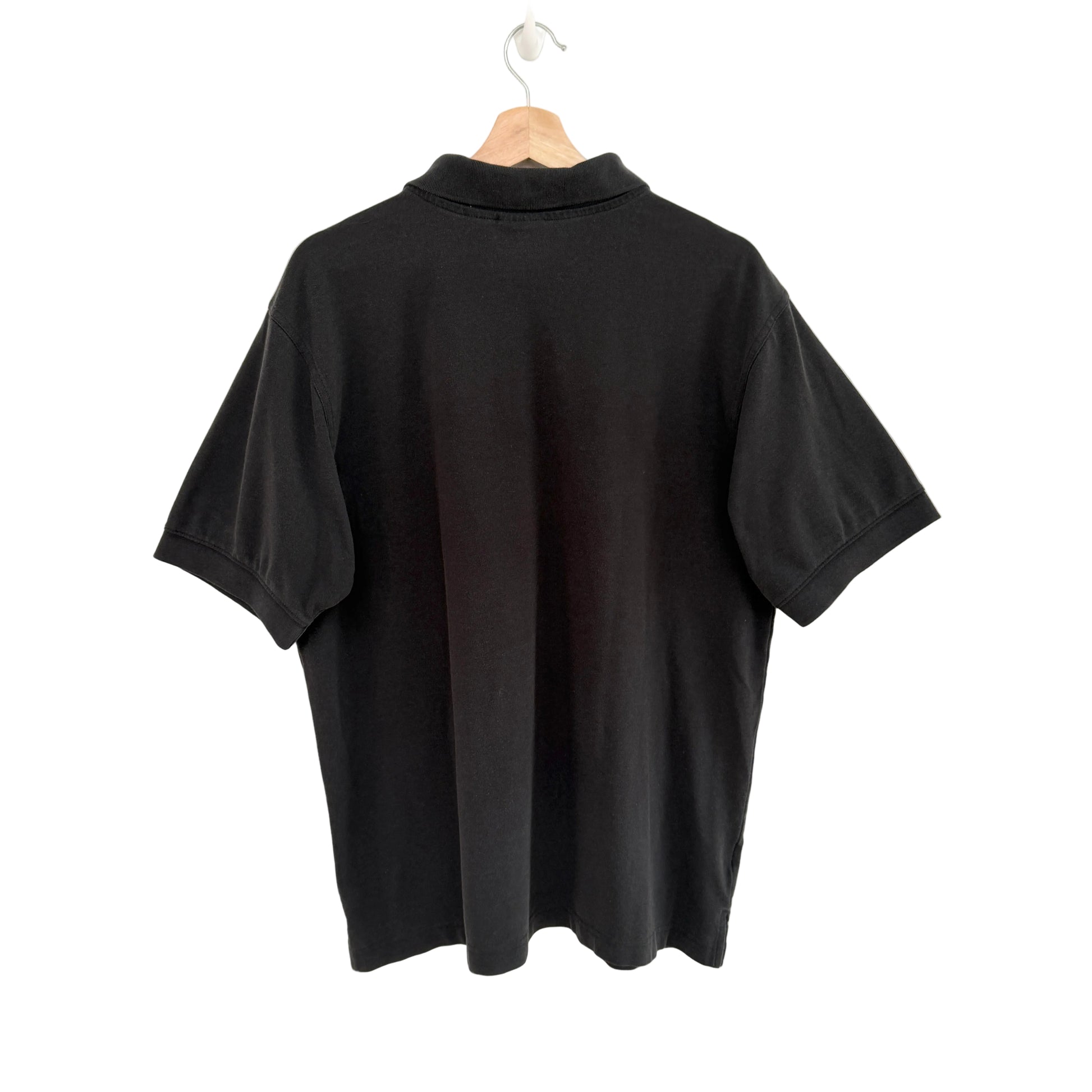 Black polo shirt on a hanger against a white background