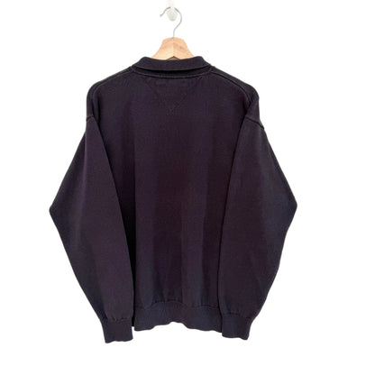Navy sweater on a hanger against a white background