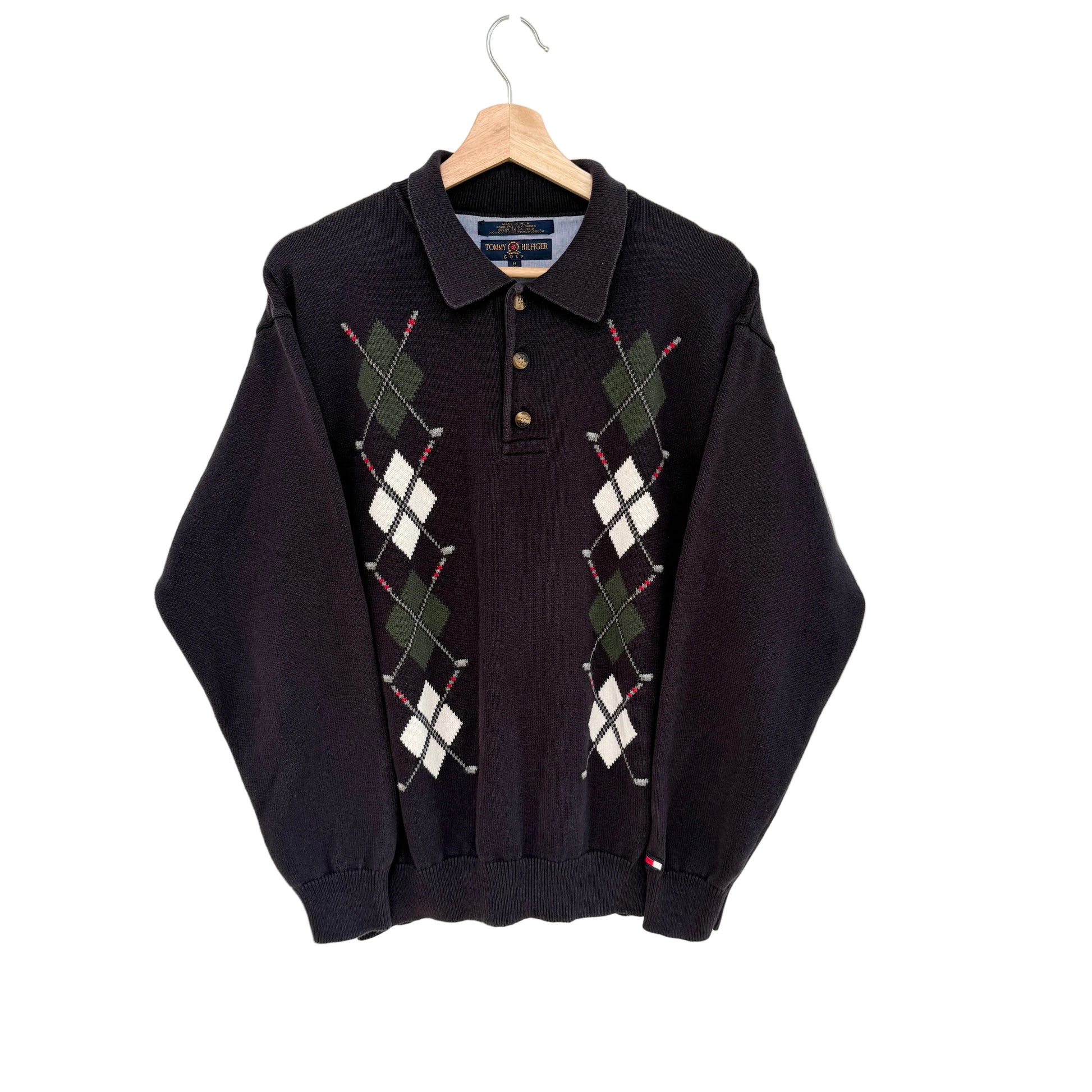 Navy argyle sweater on a hanger against a white background